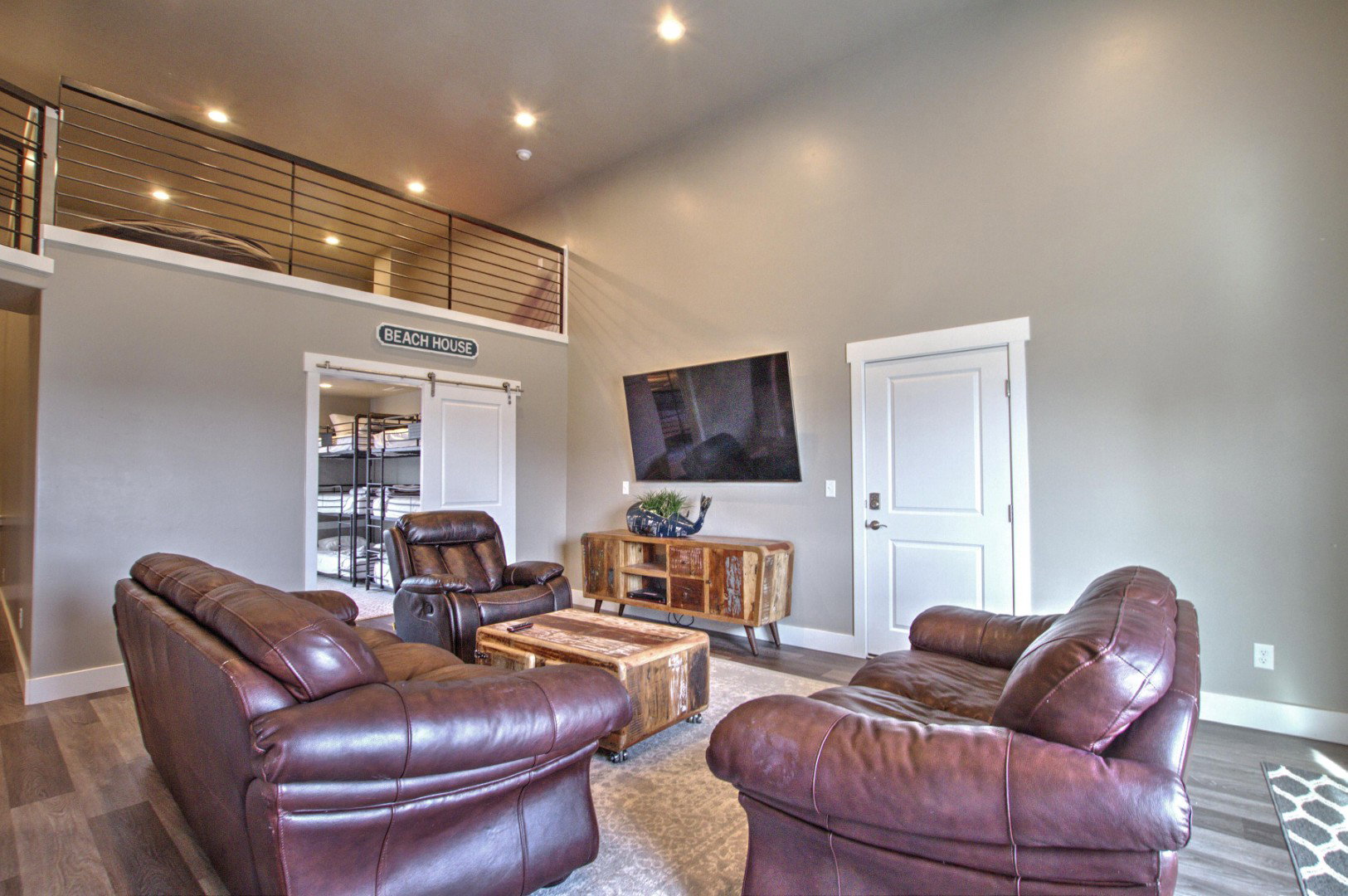 Living area with a high ceiling, recessed lighting, wood finished floors, and baseboards