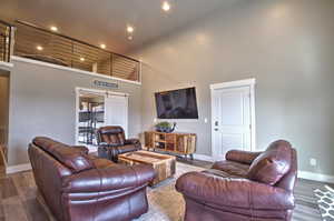 Living area with a high ceiling, recessed lighting, wood finished floors, and baseboards