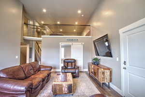 Living area featuring stairs, a high ceiling, recessed lighting, and wood finished floors