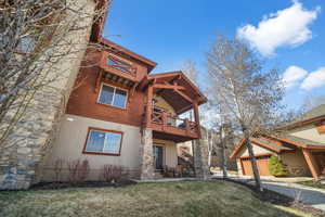 Exterior space with a patio area, driveway, a lawn, and stucco siding