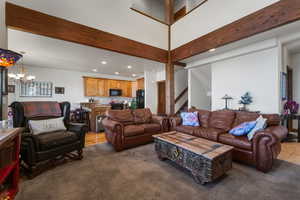 Living area with an inviting chandelier, light carpet, recessed lighting, stairs, and beam ceiling