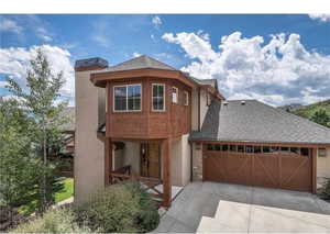 View of front of property with stucco siding, concrete driveway, an attached garage, and a shingled roof