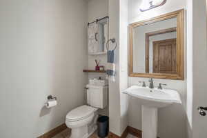 Half bath featuring baseboards, a sink, and toilet