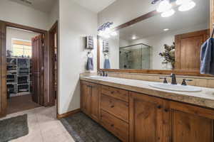Full bath featuring a shower stall, tile patterned floors, double vanity, and a sink