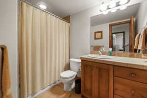 Bathroom featuring toilet, tile patterned flooring, a shower with curtain, and vanity