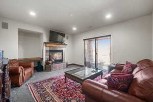 Carpeted living area featuring recessed lighting, a tile fireplace, visible vents, and baseboards