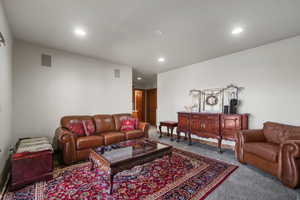 Living room with visible vents, baseboards, recessed lighting, and carpet flooring