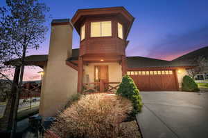 View of front of house featuring an attached garage, a shingled roof, driveway, and stucco siding