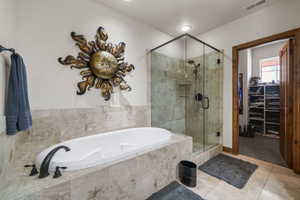 Full bath featuring visible vents, a walk in closet, a shower stall, tile patterned flooring, and a garden tub