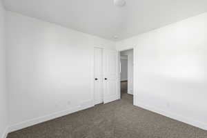Spare room featuring baseboards and dark carpet