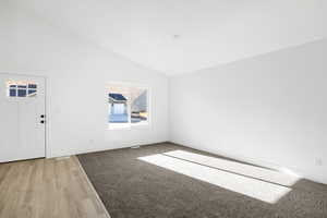 Unfurnished room featuring baseboards, vaulted ceiling, and light wood-type flooring