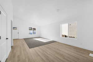 Unfurnished living room with high vaulted ceiling, baseboards, and light wood-type flooring