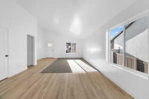 Unfurnished living room with baseboards, high vaulted ceiling, and light wood-style floors