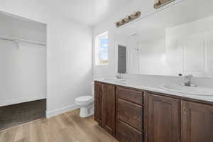 Full bath featuring double vanity, toilet, wood finished floors, and a sink