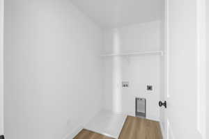 Laundry area with hookup for an electric dryer, washer hookup, baseboards, laundry area, and wood finished floors