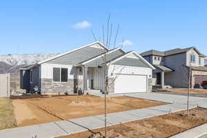 View of front of home featuring an attached garage, stone siding, board and batten siding, and concrete driveway