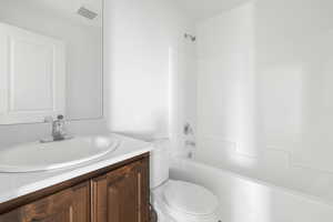 Bathroom featuring visible vents,  shower combination, toilet, and vanity