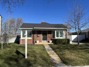 Bungalow-style home with brick siding, a chimney, and a front yard