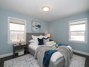 Bedroom with multiple windows, wood finished floors, and baseboards