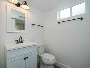 Bathroom with vanity, toilet, baseboards, and visible vents