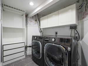 Washroom featuring cabinet space, washer and dryer, and dark tile patterned flooring
