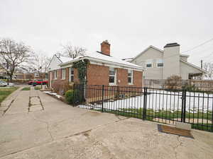 View of property exterior featuring fence, brick siding, and a chimney