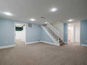 Finished basement featuring stairway, carpet, and visible vents