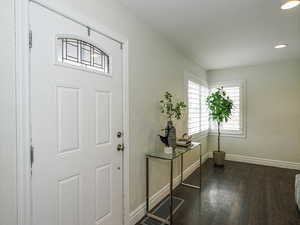 Foyer entrance featuring dark wood-type flooring, recessed lighting, visible vents, and baseboards