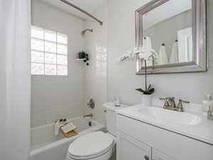 Bathroom featuring vanity, toilet, and shower / bathtub combination with curtain