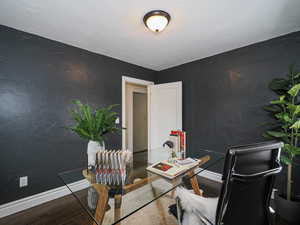 Office area featuring wood finished floors, baseboards, and a textured wall