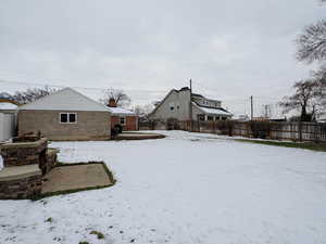 Yard covered in snow featuring fence