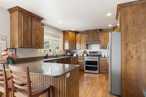 Kitchen with recessed lighting, stainless steel appliances, light wood-type flooring, and dark stone counters