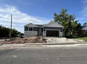 View of front of property featuring stone siding, an attached garage, and driveway