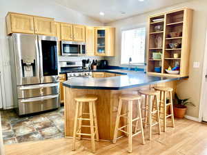 Kitchen with a sink, lofted ceiling, appliances with stainless steel finishes, and light brown cabinets