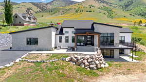 Rear view of house featuring a patio area, board and batten siding, outdoor lounge area, a deck with mountain view, and stone siding