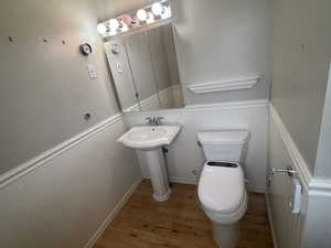 Bathroom featuring wainscoting, toilet, and hardwood / wood-style flooring