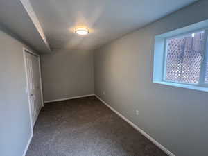 Unfurnished bedroom with a closet, baseboards, and dark colored carpet