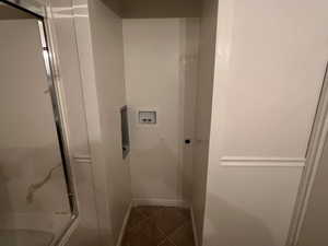 Interior space with tile patterned floors, baseboards, and a shower with shower door