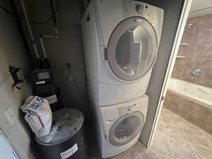 Clothes washing area featuring laundry area, light tile patterned floors, and stacked washing maching and dryer