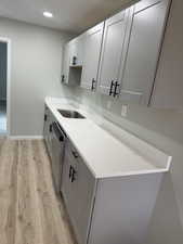 Kitchen featuring baseboards, recessed lighting, a sink, stainless steel dishwasher, and light wood-type flooring