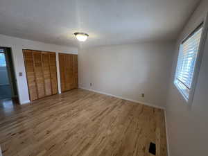 Unfurnished bedroom with multiple windows, two closets, and light wood finished floors