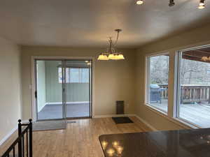 Unfurnished dining area with plenty of natural light, a textured ceiling, and light wood-type flooring