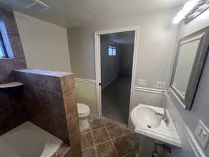 Bathroom with visible vents, a wainscoted wall, toilet, a tub to relax in, and tile patterned floors