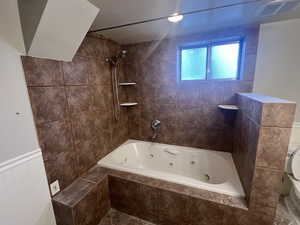 Bathroom featuring toilet, visible vents, a combined bath / shower with jetted tub, and wainscoting