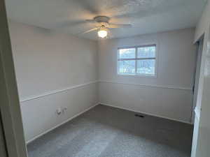 Carpeted empty room featuring baseboards, visible vents, a textured ceiling, and a ceiling fan