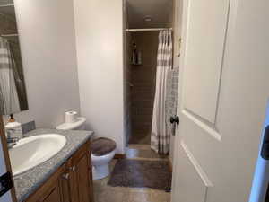 Full bath with toilet, a stall shower, and vanity