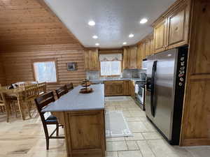 Kitchen featuring a kitchen bar, recessed lighting, brown cabinets, and stainless steel appliances