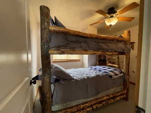 Bedroom with a ceiling fan and a textured ceiling
