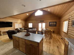 Kitchen featuring a center island, dishwasher, light wood-style flooring, rustic walls, and a textured ceiling