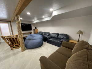 Carpeted living area featuring beamed ceiling, recessed lighting, and a textured ceiling